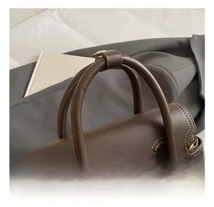 Close-up of dark brown leather handbag with contrast stitching and gold metal buckles