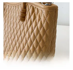 Detalle de bordado acolchado y herrajes plateados en un bolso marrón claro