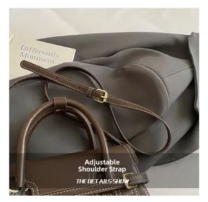 Macro detail of dark brown handbag showing adjustable shoulder strap and contrast stitching