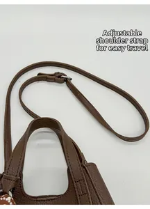 Detail of brown litchi leather bucket bag showing adjustable strap and handle grip