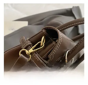 Detail of premium brown leather bag showing golden metal hook and white contrast stitching
