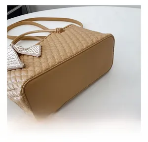 Primer plano del bolso bandolera acolchado caqui con costuras finas y colgante de lazo