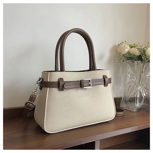 Détail du sac à main beige texturé avec lanières en cuir marron et garnitures argentées