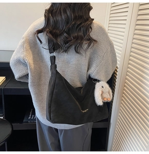 Detalle de bolso hobo de ante negro con colgante de conejo de peluche y letras doradas