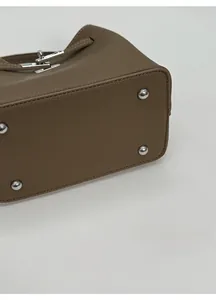 Detail of wide bag base with silver metal protective studs and pebble leather texture