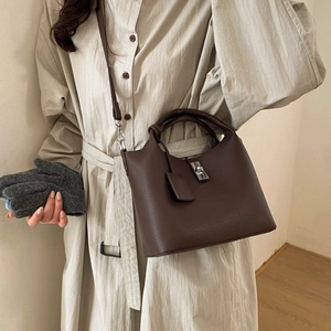 Detail of a dark brown lychee leather bucket bag with silver metal swivel lock and strap