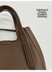 Detail of reinforced handle with precision stitching on brown lychee grain leather bag