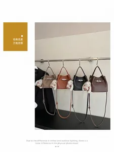 Dettaglio di borse a secchiello in quattro colori con fibbie metalliche e ciondoli