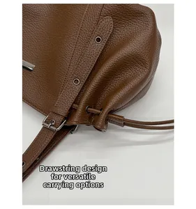 Detail of brown lychee leather tote bag with drawstring design and adjustable metal buckle