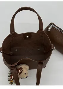 Top view of dark brown pebbled leather bucket bag with inner pouch and bear charm
