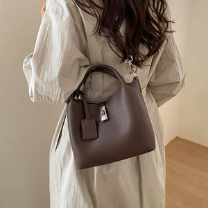 Detail of dark brown leather bucket bag showing silver lock and pebbled texture