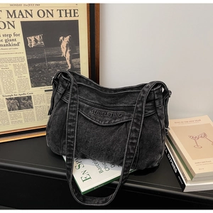 Vue détaillée du sac cabas en jean gris avec broderie posé sur des livres vintage
