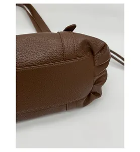 Macro detail of the reinforced bottom base on a dark brown lychee leather tote bag
