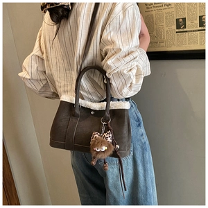 Detail of dark brown suede handbag with white faux fur trim and cute monster charm