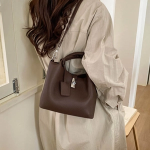 Detail of dark brown lychee leather bucket bag with silver lock and shoulder strap