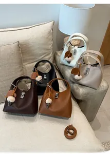 Detail view of five bucket bags in various colors featuring metal lock and charm