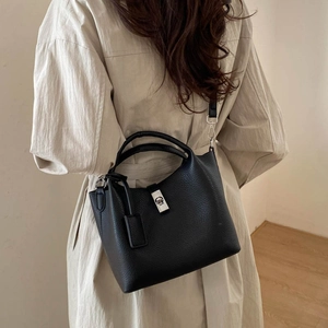 Rear view of model carrying a black pebble leather bucket bag with silver twist lock