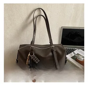 Detail of dark brown Boston bag in PU leather with cute dog charm and laptop background