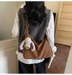 Detalle de bolso hobo de ante marrón con correa ajustable y colgante de conejo