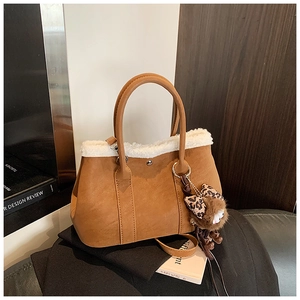 Close-up of brown suede tote bag with white plush trim and leopard print charm