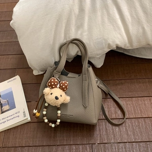 Detail of grey litchi texture bucket bag with cute bear charm and shoulder strap