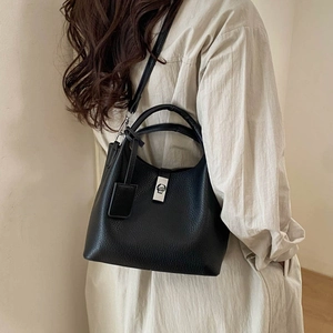 Detail of black lychee grain leather bucket bag featuring silver twist lock and strap