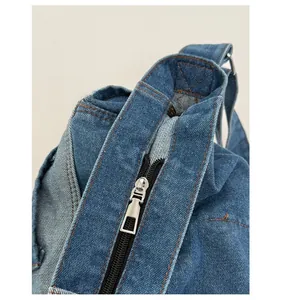 Detail shot of a blue denim tote bag featuring a high-quality silver metal zipper