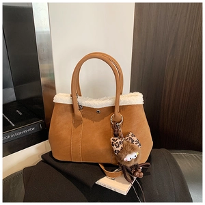 Detail of brown faux leather Boston bag with white fur trim and plush monster charm