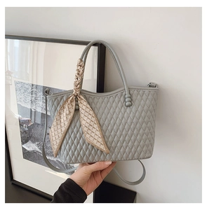 Detalle de bolso acolchado gris claro con pañuelo de seda decorativo en el asa