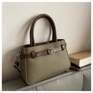 Détail du sac bandoulière en toile verte et cuir marron avec boucle métallique