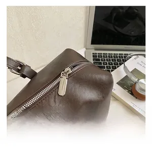 Detail of premium silver metal zipper on a dark coffee textured leather tote bag