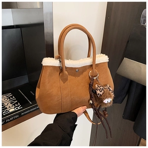 Close-up of brown suede bucket bag with white plush trim and leopard bow charm