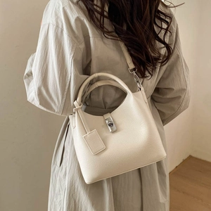Detail of creamy white pebble leather bucket bag with silver twist lock and strap