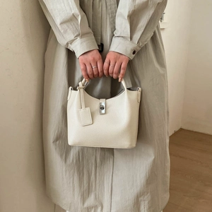 Detail of cream white pebbled leather bucket bag with silver twist lock and hangtag