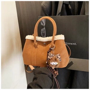 Detail of brown faux suede tote bag featuring white faux fur trim and cute plush charm