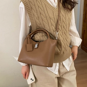 Close-up of brown litchi leather bucket bag with silver metal buckle and top handle