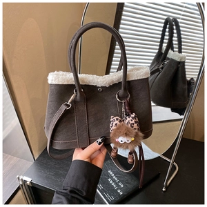 Detail of dark brown tote bag with white faux fur trim and leopard bow charm