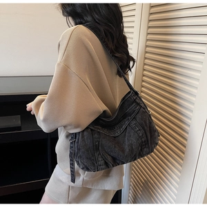 Détail du sac hobo en jean noir délavé avec broderie blanche et bandoulière réglable