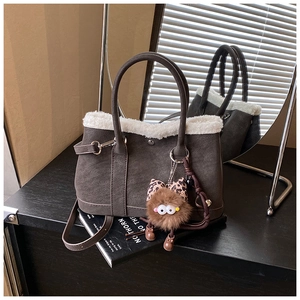 Detail of dark brown bucket bag with white faux fur trim and plush monster charm