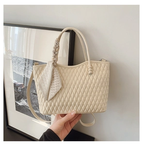 Detalle de bolso acolchado crema con elegante pañuelo de seda envuelto en el asa
