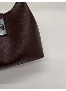 Detailed macro of pebble-grain leather texture and silver turn-lock on the bucket bag