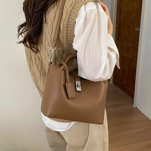 Detail of brown leather bucket bag with silver twist lock and adjustable shoulder strap