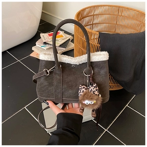 Detail of dark brown bucket bag featuring white faux fur trim and leopard bow charm