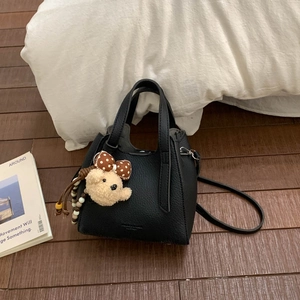 Detail of black lychee grain PU leather bucket bag with a cute bear plush pendant