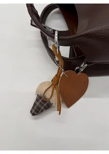Detail of plaid plush ice cream charm and heart leather tag on brown lychee bucket bag