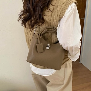 Detail view of khaki pebbled leather bucket bag styled on model with crossbody strap