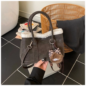 Close-up of a brown tote bag with white faux shearling trim and cute plush charms