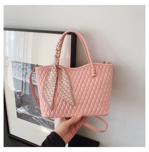 Detalle de bolso acolchado rosa con asa envuelta en seda y correa larga al hombro