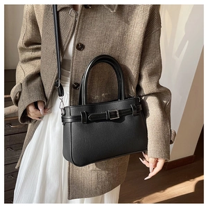 Détail d'un sac à main en cuir noir avec boucles argentées et bandoulière réglable