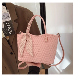Detalle de bolso acolchado rosa con pañuelo de seda de estampado geométrico en el asa